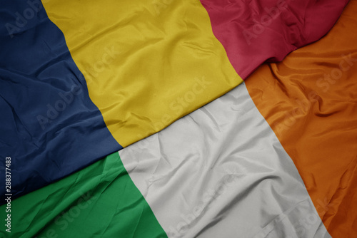 waving colorful flag of ireland and national flag of chad.