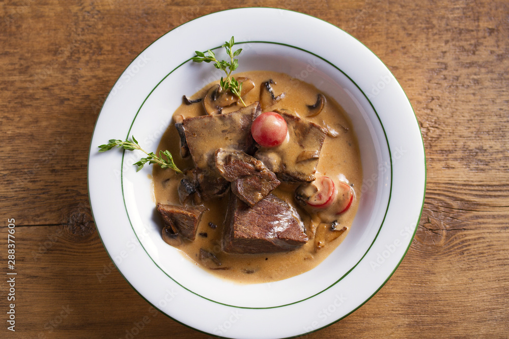 Braised veal cheeks in cream sauce with mushrooms. View from above, top studio shot - horizontal Braised veal cheeks in cream sauce with mushrooms. View from above, top studio shot - horizontal