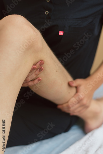 Masseur doing massage the knee to the young man. The doctor massages the leg for treatment