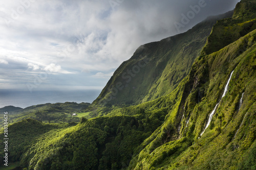 aerial landscape image of sunset sunrise over Poço Ribeira do Ferreiro waterfalls with its remarkable amazing tropical like green vegetation and forests at the Ilha das Flores island on the Azores photo