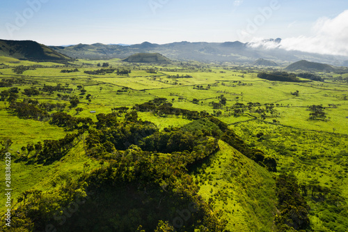 Fototapeta Naklejka Na Ścianę i Meble -  Aerial image of typical green volcanic caldera crater landscape with volcano cones of Planalto da Achada central plateau of Ilha do Pico Island, Azores