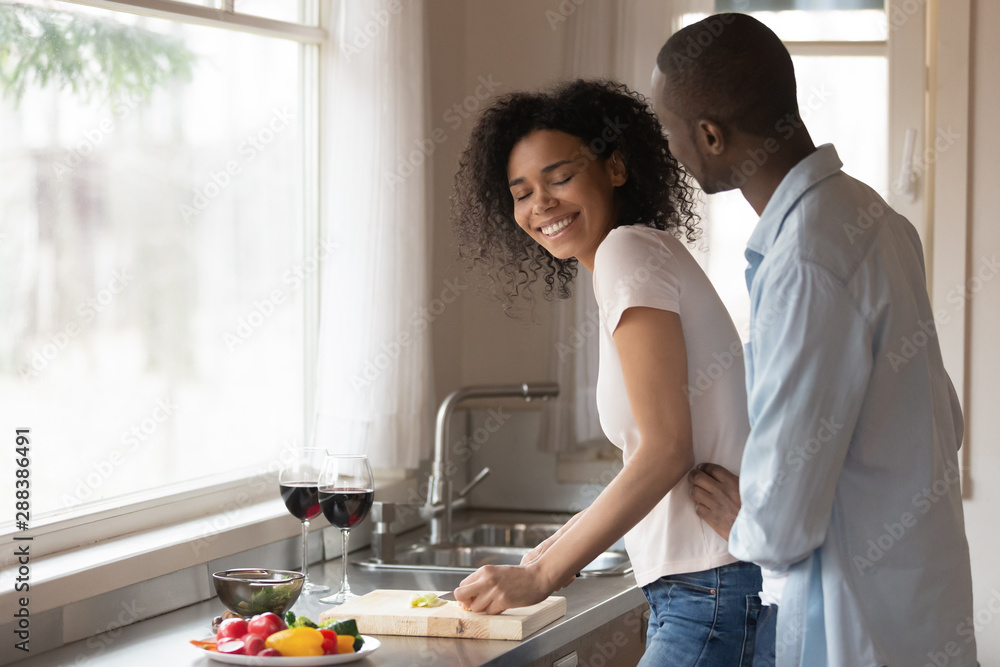 Happy biracial couple hug cooking together in kitchen Happy biracial couple hug cooking together in kitchen