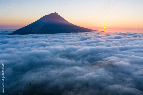 Aerial image with magical sunset over a low cloud layer covering Pico Island, with Ponta do Pico (Mount Pico)
