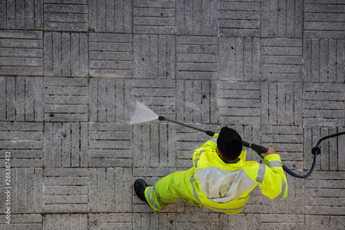 Obraz na plátne Worker cleaning the street sidewalk with high pressure water jet