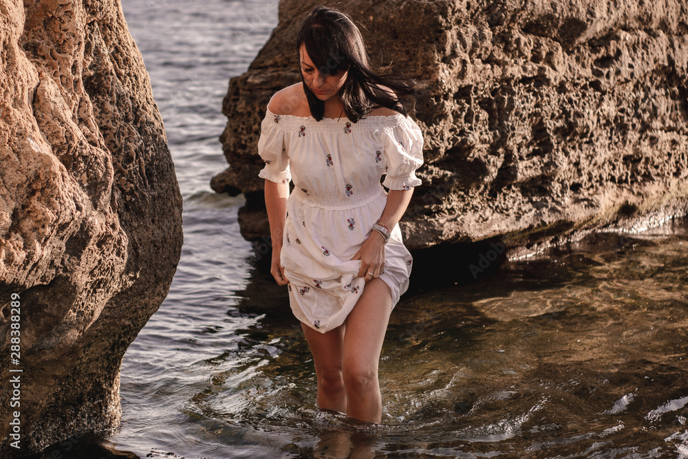 Fototapeta premium beautiful young brunete woman enjoys the beautiful view on the beach and has a good sunrise time. Relax