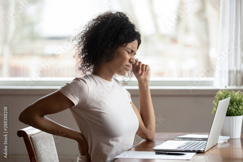 Photos Hurt biracial woman work at laptop suffer from spinal spasm