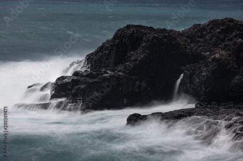 Rough seas with a slow shutter image of tide hitting the volcanic lava coastline of Sao Miguel.