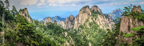 Panorama with pine trees in the foreground and rough rocky peaks leading to the horizon in Huang Shan (黄山, Yellow Mountains) China