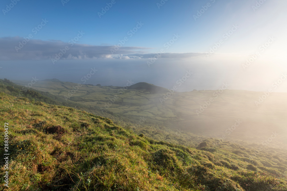 early morning landscape view on the green fields at the north coast of the Azores island of Sao Jorge, as seen from the central mountains near Pico de Esperanca.