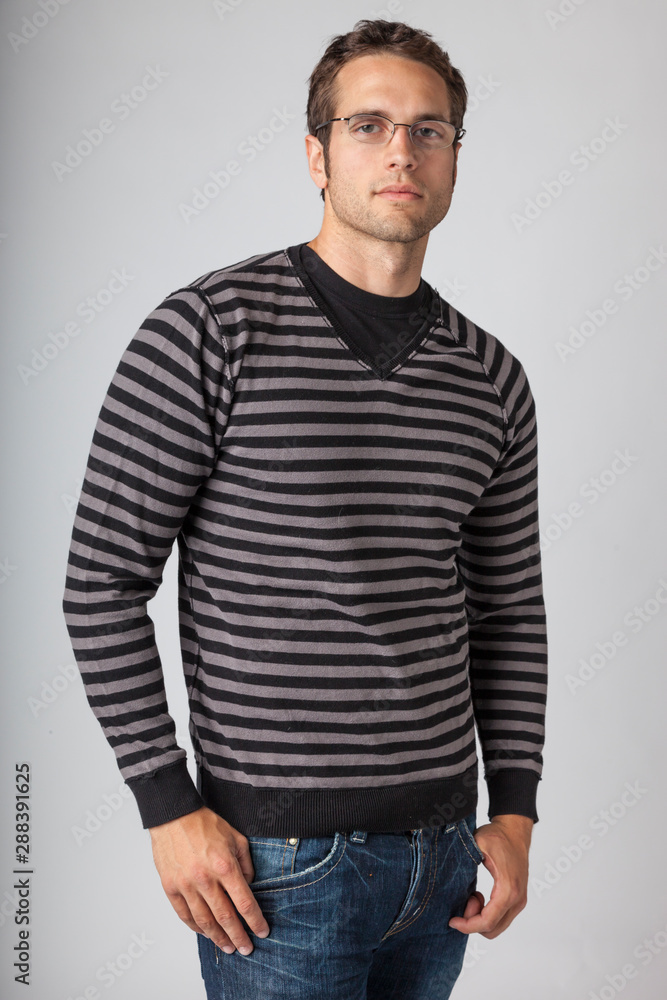 Man wearing striped sweater, jeans and eyeglasses. Young men's casual fall clothing apparel fashions styles. Man wearing striped sweater, jeans and eyeglasses. Young men's casual fall clothing apparel fashions styles.
