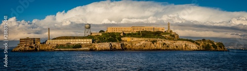 Schilderij op canvas Panorama of Alcatraz Island with grand white clouds behind the old buildings on