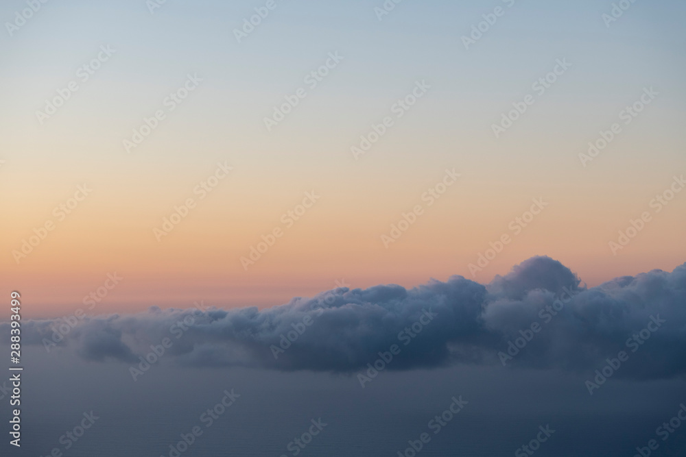 scenic image of a layer of clouds haging over the sea after sunset with a pink sky scenic image of a layer of clouds haging over the sea after sunset with a pink sky