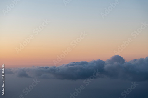 scenic image of a layer of clouds haging over the sea after sunset with a pink sky