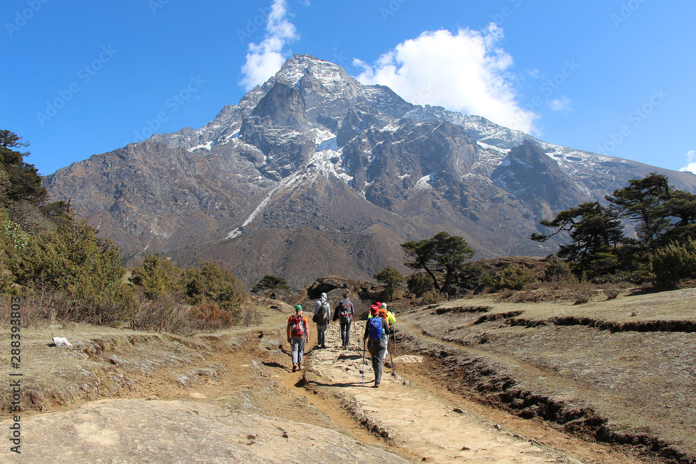Travelers follows the route towards Khumbila Mountain in Sagarmatha national park in Nepal. Nature, people, healthy lifestyle, outdoors, altitude sickness, travel and tourism concept.