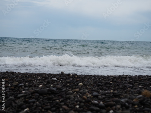 Sea waves on a pebble beach. Sea on a cloudy summer or autumn day