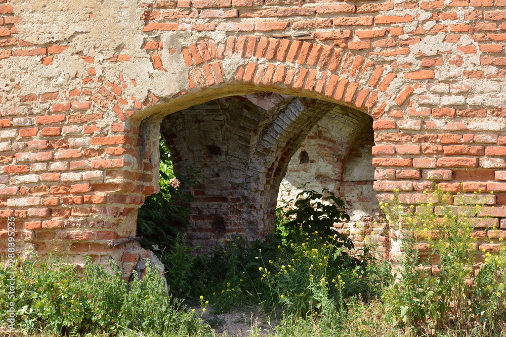 Ruins of cartesian monastery. The wall made of red brick with arched entrance.