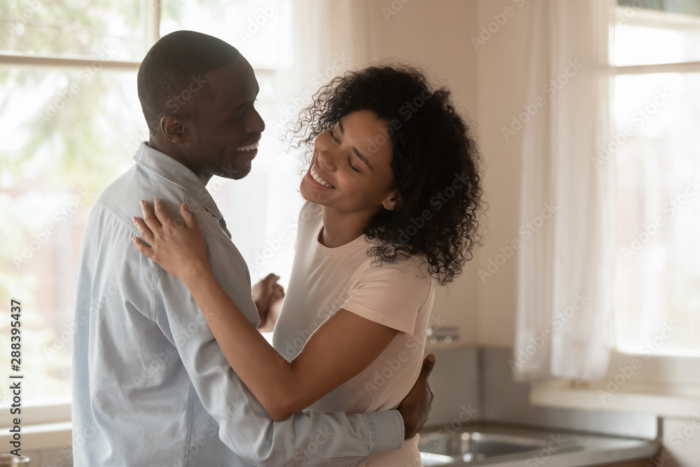Obraz premium Loving biracial couple dance in kitchen celebrating anniversary