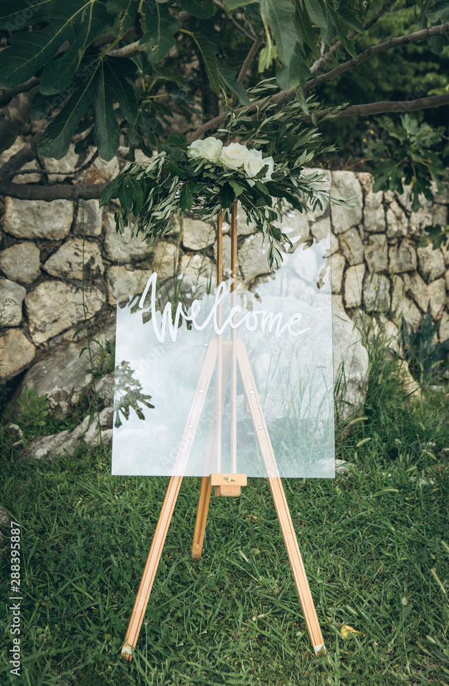 An easel decorated with flowers at a wedding event at which the inscription is welcome.