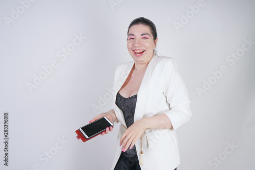charming mix race plus size woman in a white business jacket standing with smart phone in hand on white background in Studio