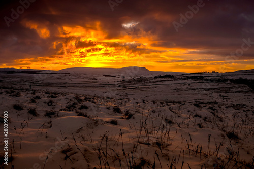 sunrise over penyghent covered in snow