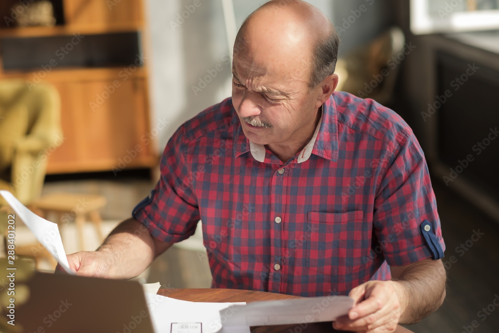 Senior hispanic man with mustache holding plan of new flat deciding to make an investment. Mortgage at old age. Buy flat for your children concept. Senior hispanic man with mustache holding plan of new flat deciding to make an investment. Mortgage at old age. Buy flat for your children concept.