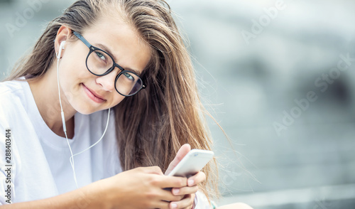 Young teenage girl with headphones enjoying with good music. Modern young woman with cellphone