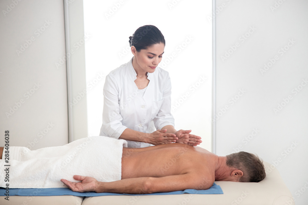 Fototapeta premium Female massage therapist doing therapeutic back massage