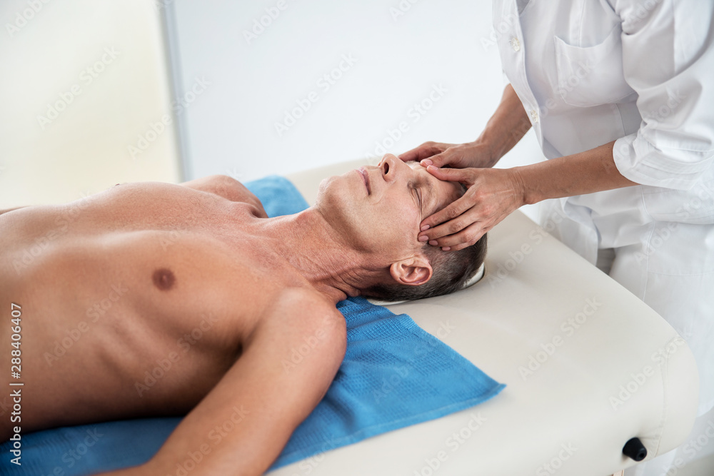 Female medict is massaging the temple for patient Female medict is massaging the temple for patient