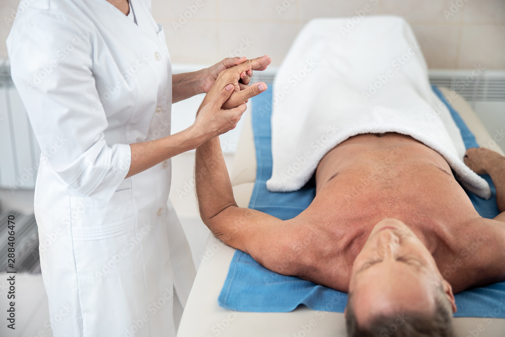 Female doctor is flexing male patient arm Female doctor is flexing male patient arm