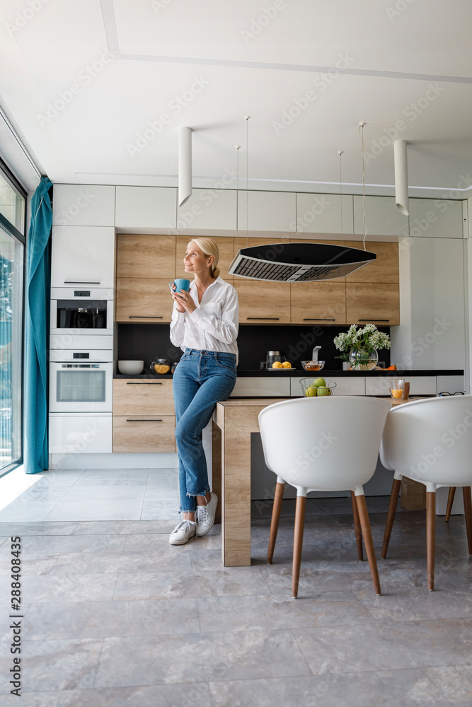 Smiling adult lady is looking away in the kitchen Smiling adult lady is looking away in the kitchen