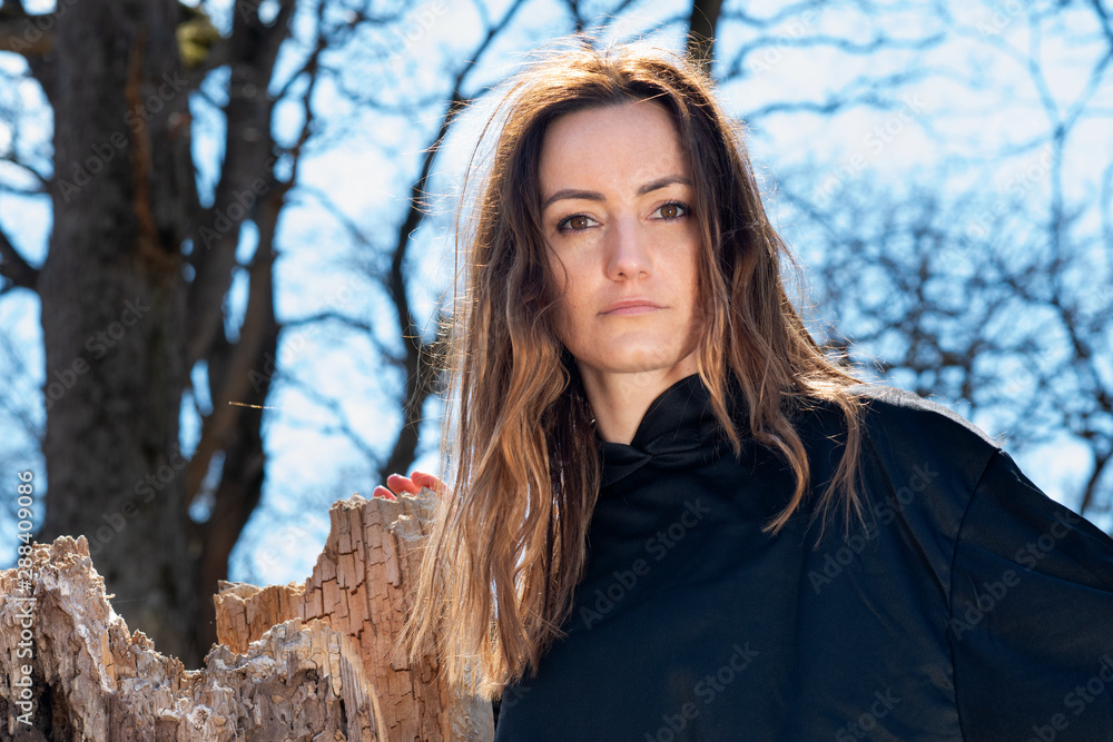 Young tall Woman with dark long hair in black robes deep in the Forest. Witches. Halloween and Gothic concept. Witchcraft and magic. Young tall Woman with dark long hair in black robes deep in the Forest. Witches. Halloween and Gothic concept. Witchcraft and magic.