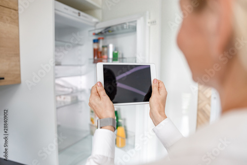 Woman is using tablet to managing fridge