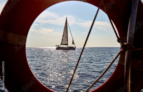 Sailing yacht visible through lifebuoy © Karas Nur Li