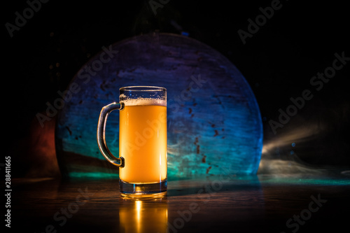 Creative concept. Beer glasses on wooden table at dark toned foggy background.