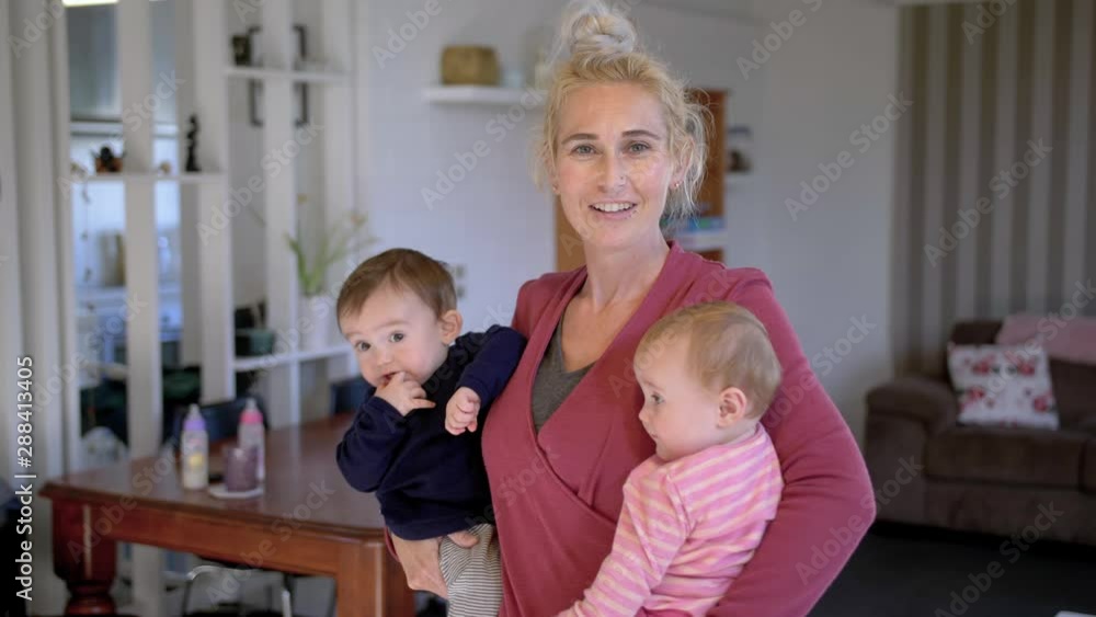 Mother holding her twin babies and moving them around, looking at the camera. Mother holding her twin babies and moving them around, looking at the camera.