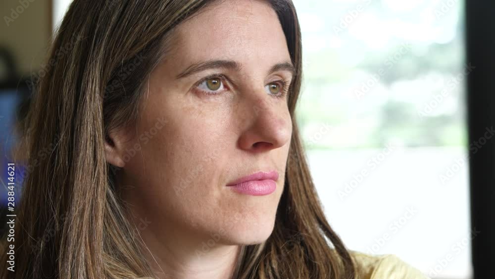 Close-up profile shot of an authentic pensive brunette woman lost in thought staring out a bright window. Close-up profile shot of an authentic pensive brunette woman lost in thought staring out a bright window.