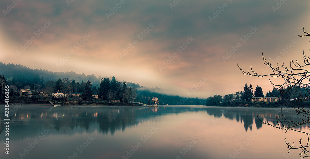 Fototapeta premium Riverwood and Milwaukie on opposite sides of the Willamette River, Cloudy sky, still water, long exposure, seen from Milwaukie Bay Park at dawn
