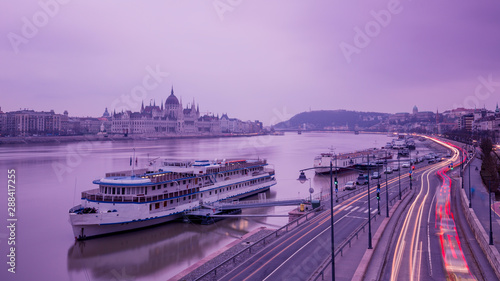 Obraz na płótnie Cityscape of Budapest with parliament and Danube river in overcast sky and cold light. Purple colors, sky reflecting in water and light tracks from moving cars. w salonie