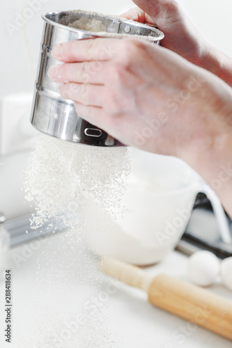 Sift flour. Hands cooks close-up. Baker sifts the flour before making bread. Chef prepares the dough for pizza. Hand sifts through sieve, falling flour is frozen. Flour falls in motion table.