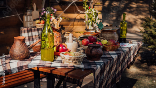 A laid table in a rustic style on the street. An exhibition of rustic interior. rural still life table. Still life with ripe apples and a bottle of moonshine