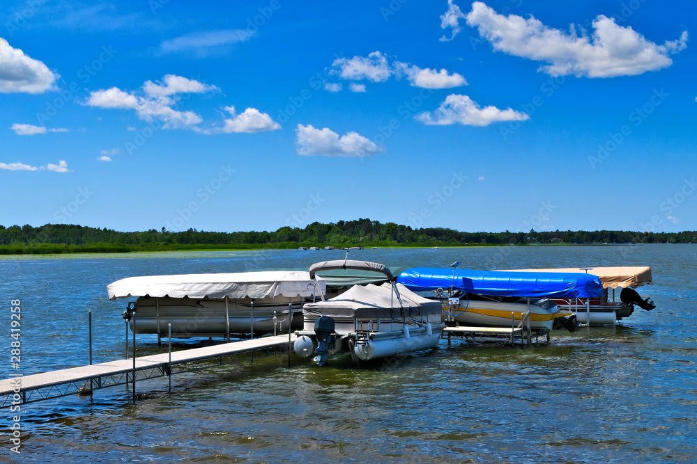 Boat dock with raised pontoons on beautiful lake in northern Minnesota with blue sky and fluffy clouds. Boat dock with raised pontoons on beautiful lake in northern Minnesota with blue sky and fluffy clouds.