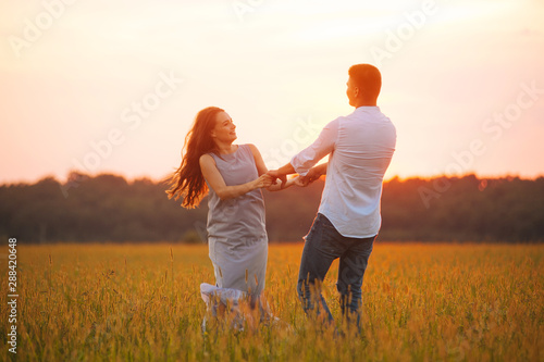 Photo of couple dancing in a file on sunset, having fun