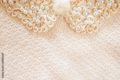 Beaded ribbon and woven fabric background with soft fluffy button decoration off white in colour and shot from above