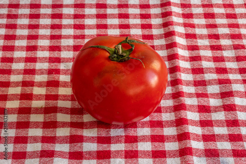 A kaki fruit over a red and white checkered cloth 