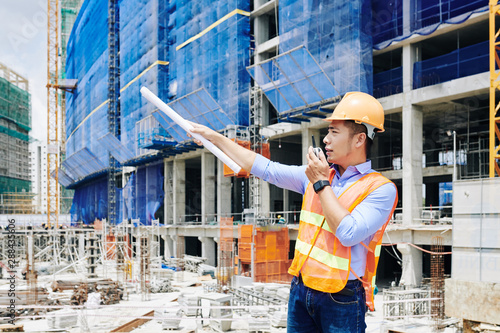 Young Vietnamese civil engineer managing process of work at construction site