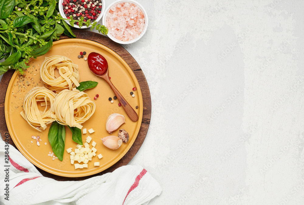 Ingredient for simple italian dinner on yellow plate. Fettuccine, fresh basil, tomato souce and mozzarella cheese