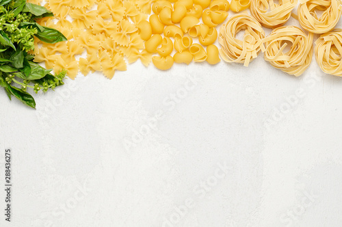 Obraz na płótnie Different types of Italian pasta and fresh basil. Farfalle, Pipe rigate and Fettuccine on light grey background w salonie