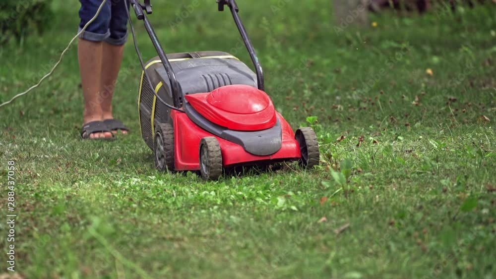 Lawn mower cutting green grass. Closeup of man mowing the grass with lawn mower Lawn mower cutting green grass. Closeup of man mowing the grass with lawn mower
