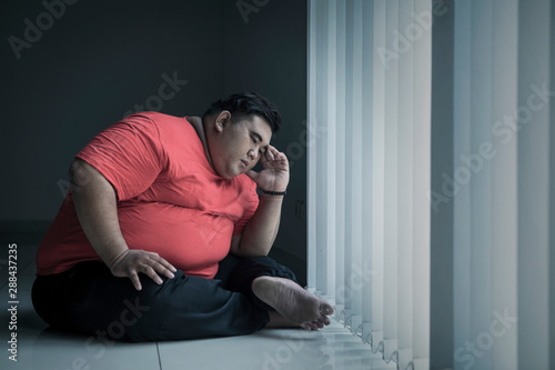 Canvastavla Young obese man looks stressed near the window
