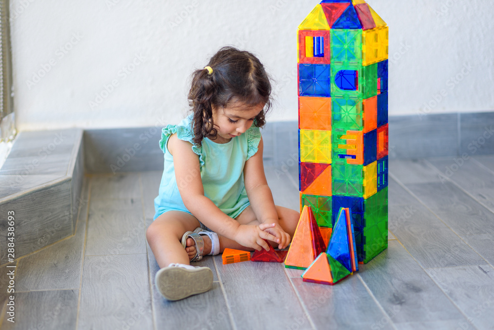 Little girl playing with lots of colorful plastic blocks constructor ...